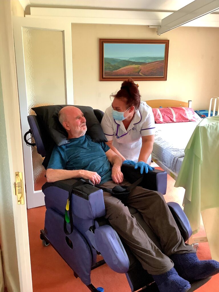 Man smiling with carer during care visit: Parkinson's Disease